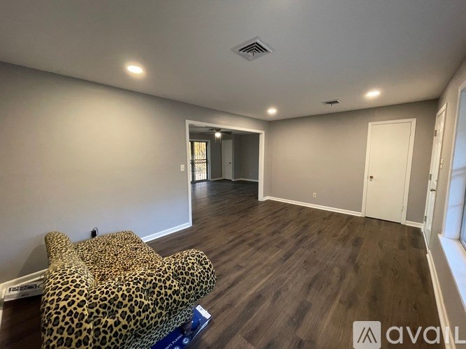 A leopard print chair sits in a room with wood flooring and a ceiling fan.
