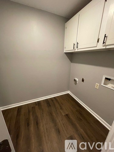 A room with wooden flooring and white cabinets.