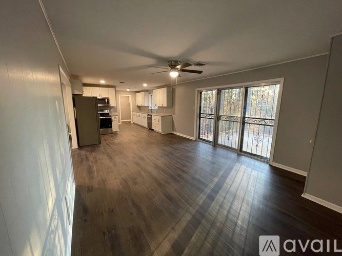 A spacious living room with hardwood floors and a ceiling fan.