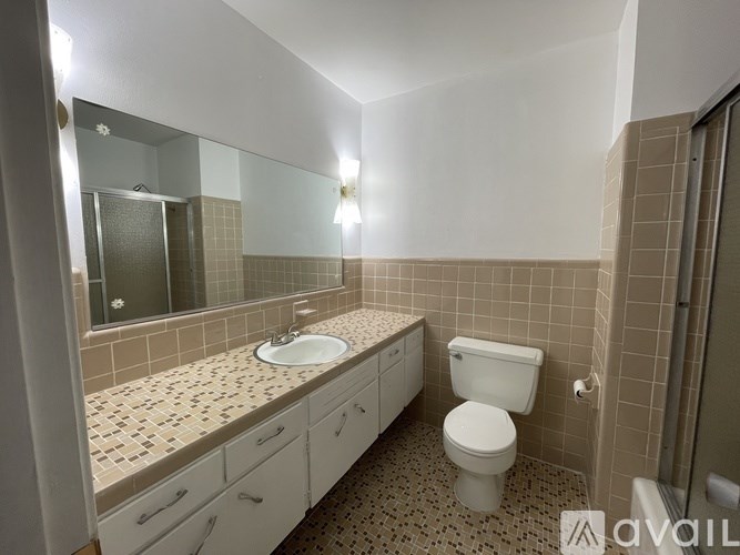 A bathroom with a toilet, sink, and mirror.
