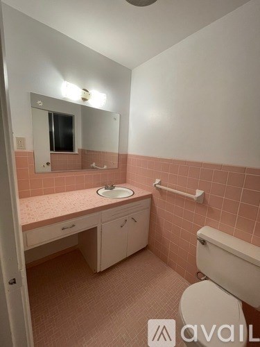A bathroom with pink tiles and a white toilet.