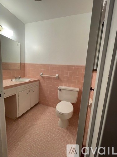 A bathroom with a toilet, sink, and pink tiles.