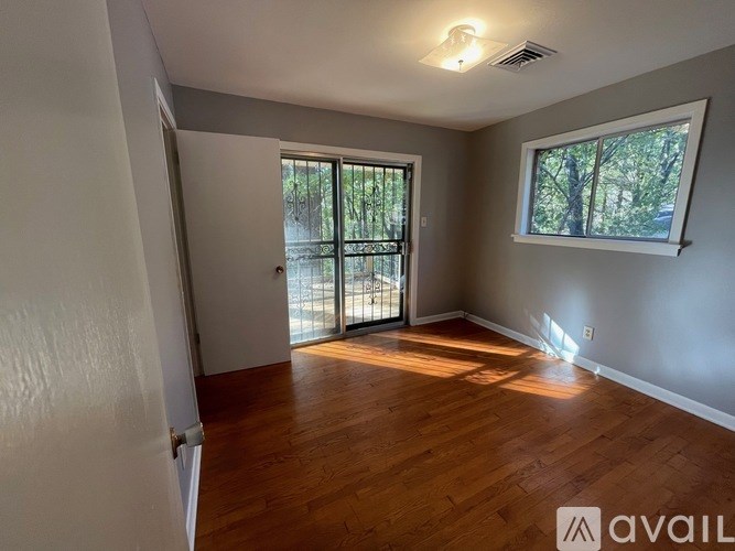 A room with wooden floors and a window with a view of trees.