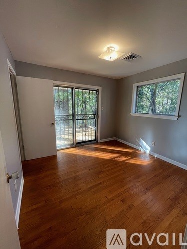 A room with wooden floors and a window overlooking a tree-filled area.