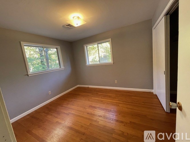 A room with wooden floors and two windows.