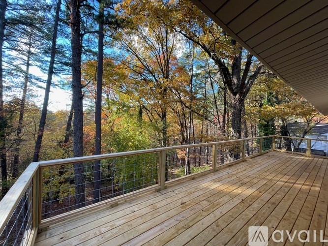 A wooden deck with a metal railing overlooks a forest.