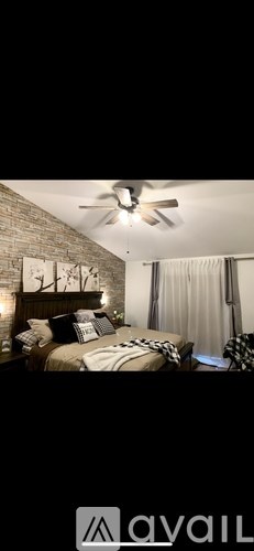 A bedroom with a brick wall and a ceiling fan.
