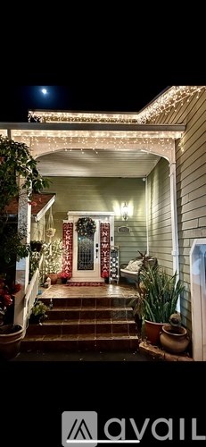 A house entrance decorated with Christmas lights and a red door.