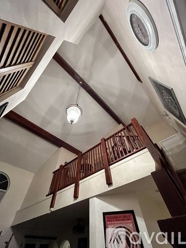 A white ceiling with a wooden balcony and a light hanging from the ceiling.