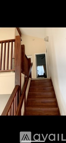 A wooden staircase with a railing on the left side leading to a doorway.