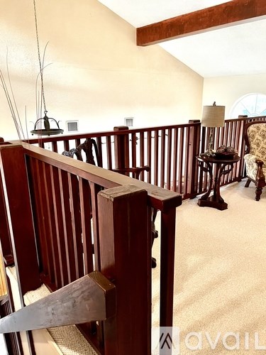 A living room with a couch, chairs, and a hanging plant.