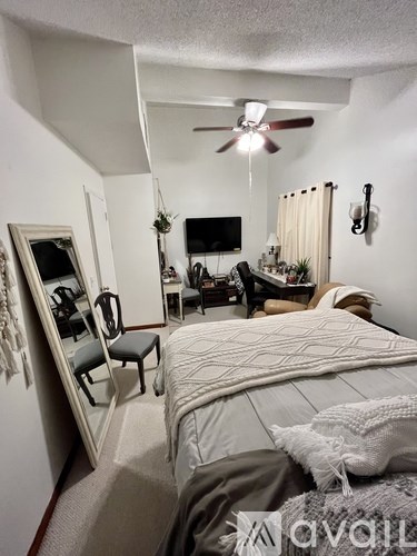 A bedroom with a bed, chair, and a ceiling fan.