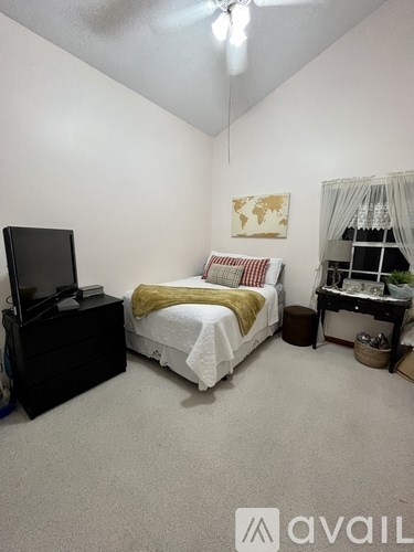 A bedroom with a bed, dresser, and television.