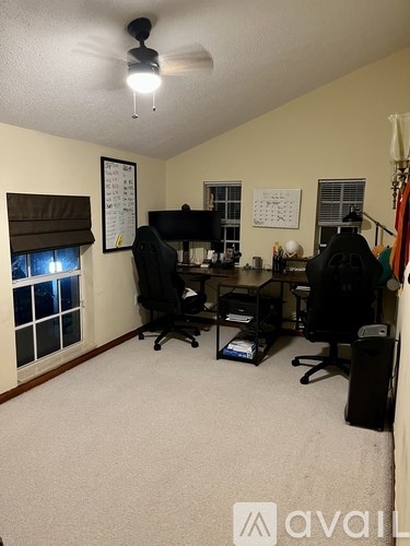 A room with a desk, chairs, and a computer setup.