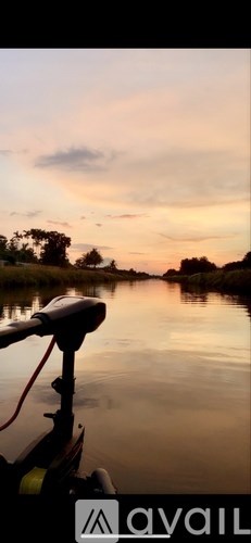 A boat is docked on a river with a beautiful sunset in the background.