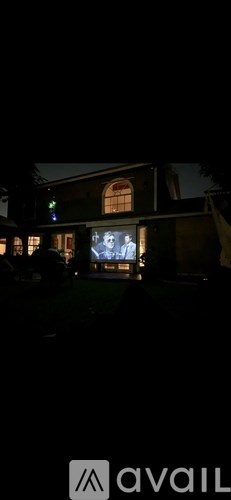 A dark scene with a building and a screen displaying an image.