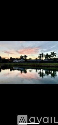 A serene landscape with a body of water and palm trees.