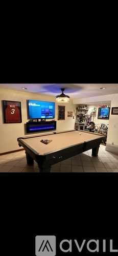 A room with a pool table and a TV mounted on the wall.