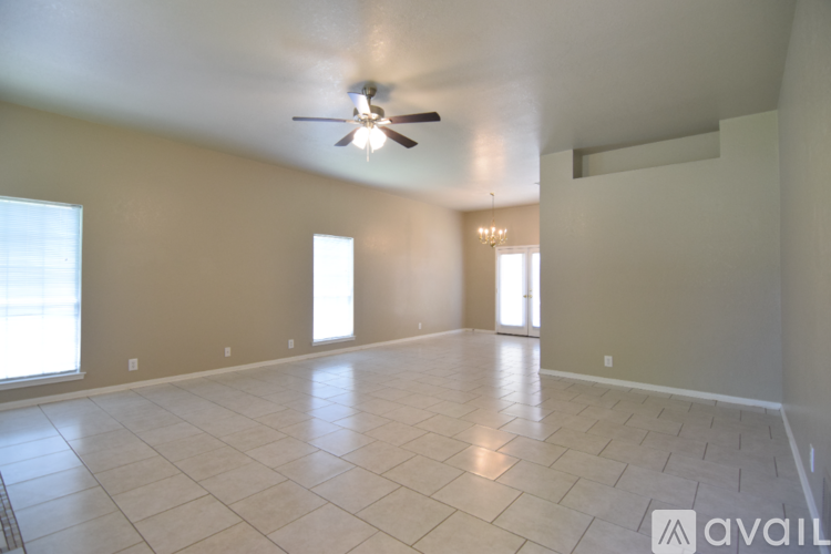 A spacious room with a ceiling fan and two windows.