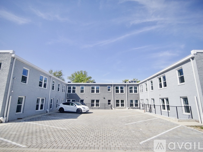 A white car is parked in a parking lot in front of a grey building.