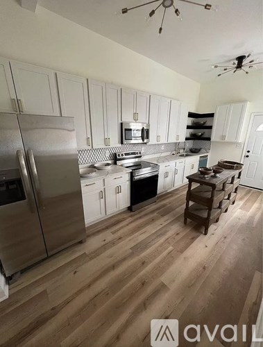 A kitchen with wooden floors and white cabinets.