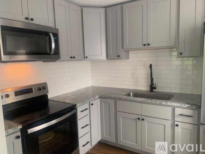A kitchen with white cabinets and a black stove top oven.