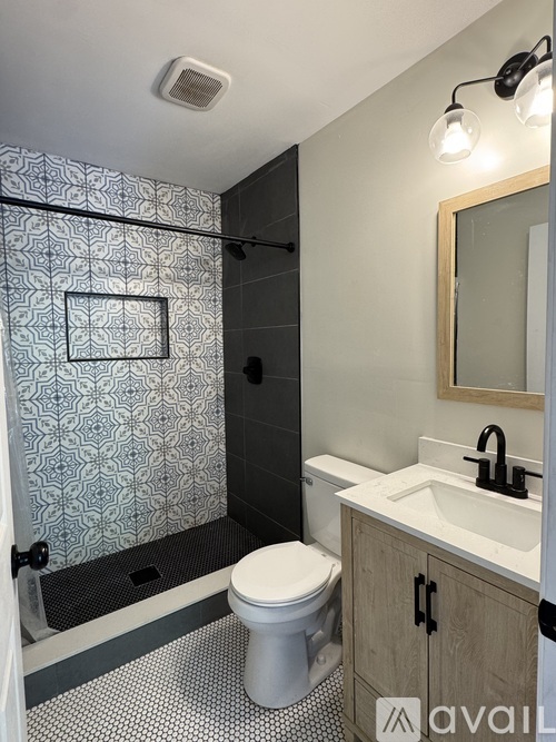 A shower with a grey and white tiled wall.