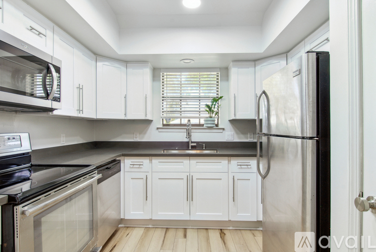 A kitchen with white cabinets and a black refrigerator.