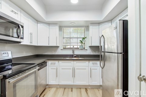 A kitchen with white cabinets and a black refrigerator.