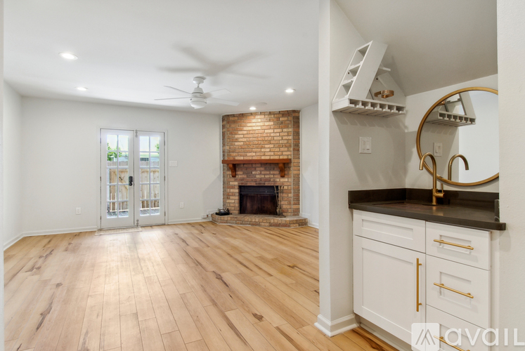 A spacious living room with a fireplace and a ceiling fan.