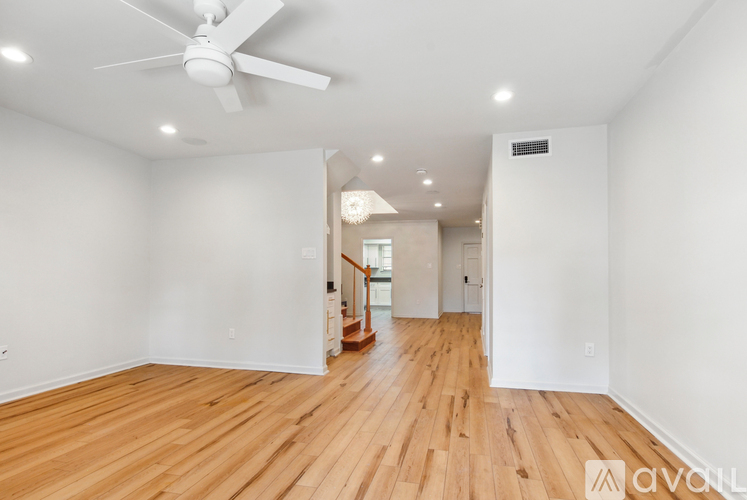 A spacious room with wooden floors and a ceiling fan.
