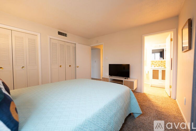 A bedroom with a bed, a television, and a window.