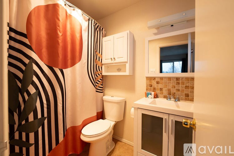 A bathroom with a toilet, sink, and shower curtain.