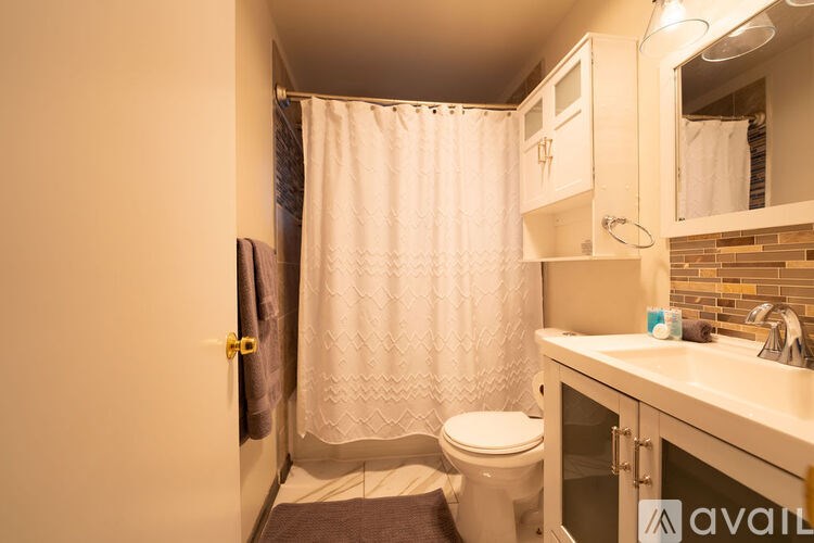 A small bathroom with a toilet, sink, and shower.