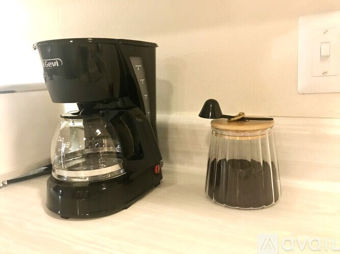 A black coffee maker with a glass carafe on a white counter.