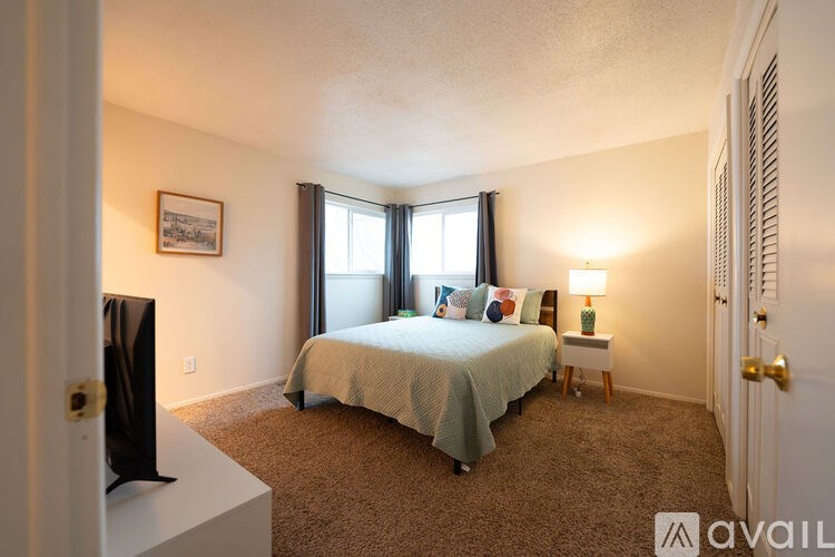 A bedroom with a bed, a television, and a window with blinds.
