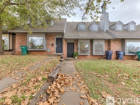 A house with a black door and windows surrounded by fallen leaves.