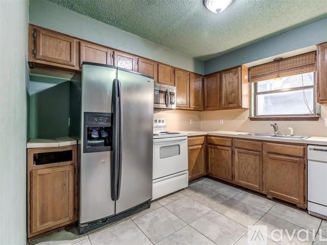 A kitchen with wooden cabinets and a stainless steel refrigerator.
