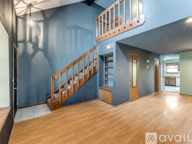 A spacious room with wooden stairs and a blue wall.