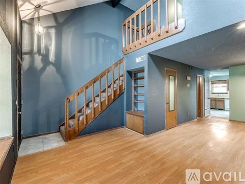 A spacious room with wooden stairs and a blue wall.