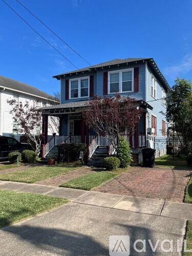 A two-story house with a red door and a brick walkway in front.