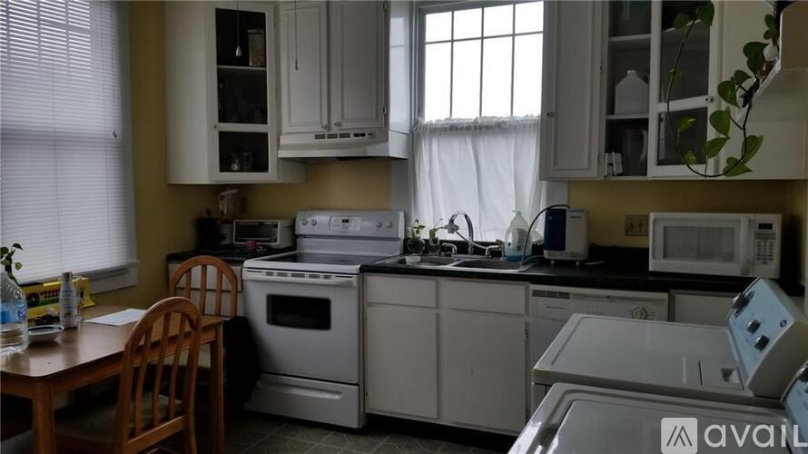 A kitchen with white appliances and a wooden chair.