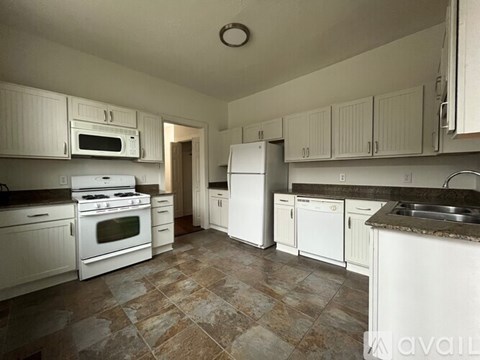 A kitchen with white appliances and a wooden chair.