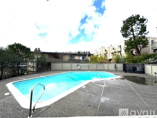 A small pool in a backyard surrounded by a black fence.