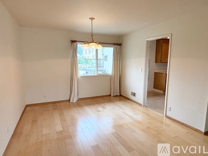 A room with wooden flooring and a window with curtains.
