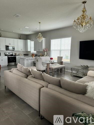 A living room with a beige couch and a chandelier.