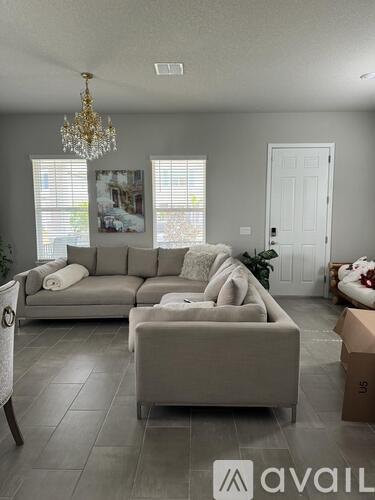 A living room with a grey sofa and a chandelier.