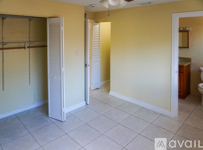 A room with a white fridge and a fan on the ceiling.