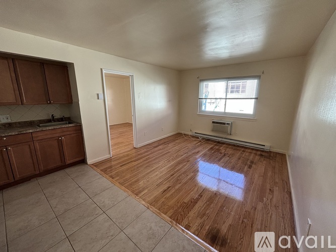 A room with wooden flooring and a window with a white frame.
