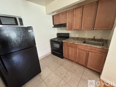 A kitchen with black appliances and brown cabinets.